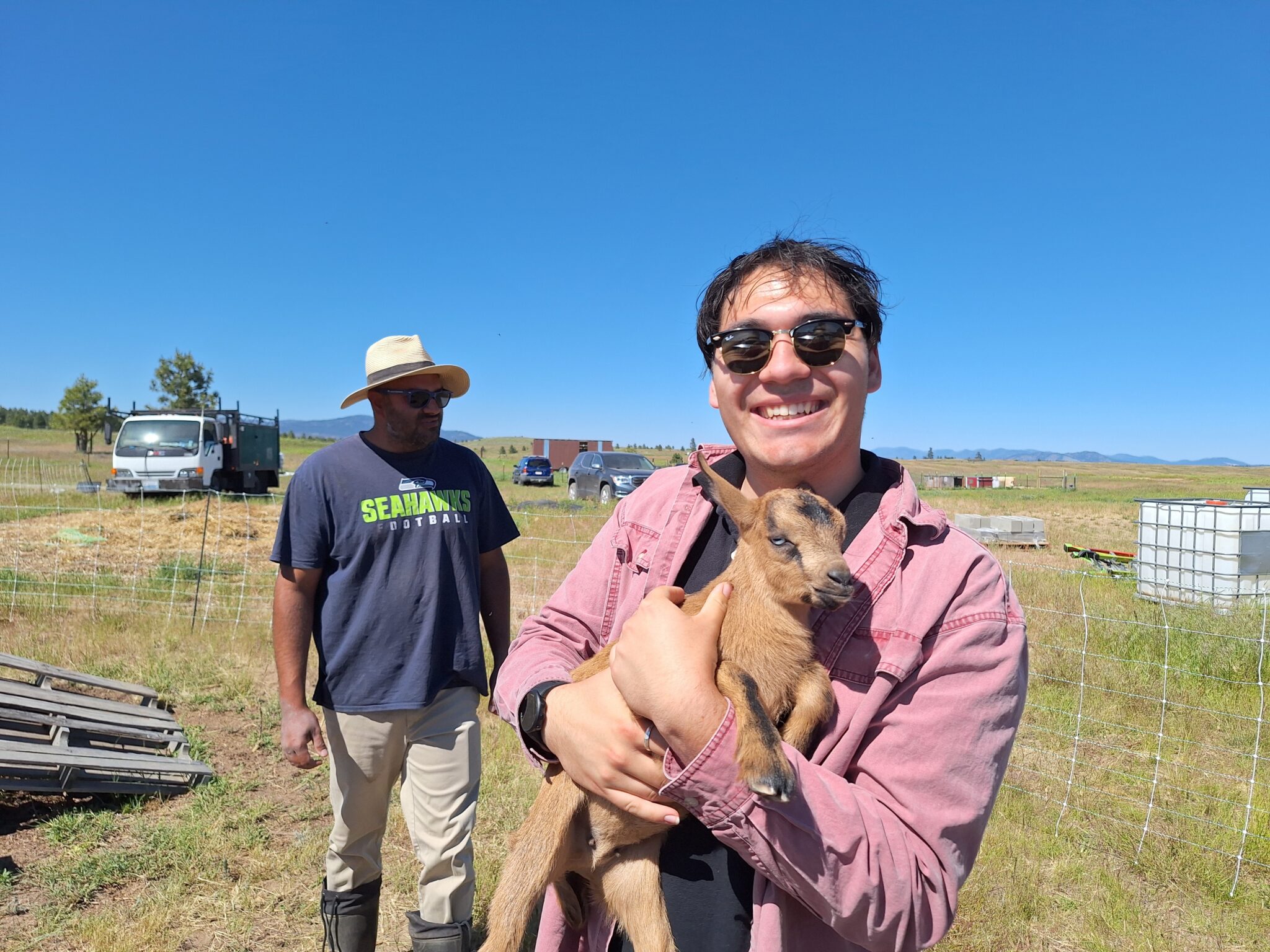 Kyle smiling with a baby goat at a site visit in Creston, Wash. Part of the role was to go and learn from field staff, and visiting producers like this goat farmer.